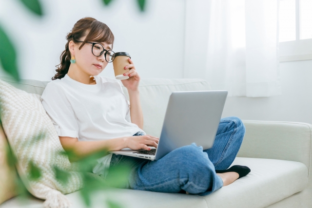 パソコンを膝の上において画面を見る女性